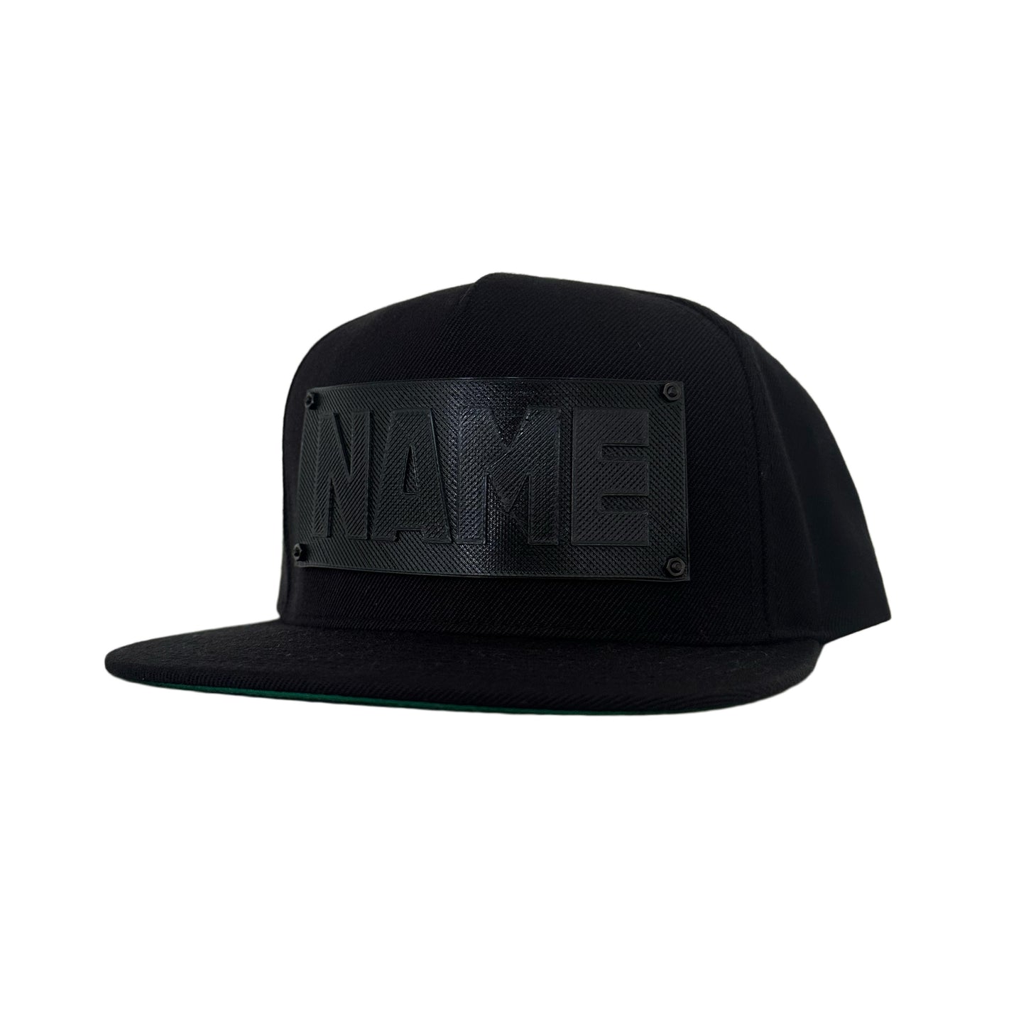 A black snapback baseball hat with a black logo panel that says"NAME".