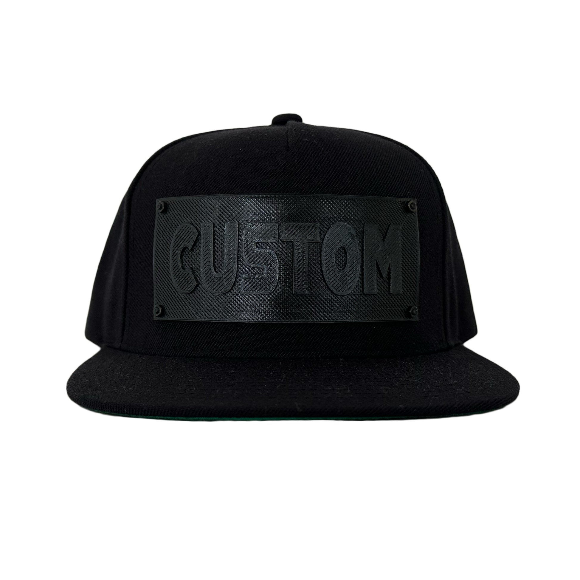 A black snapback baseball hat with a black logo panel that says"CUSTOM".