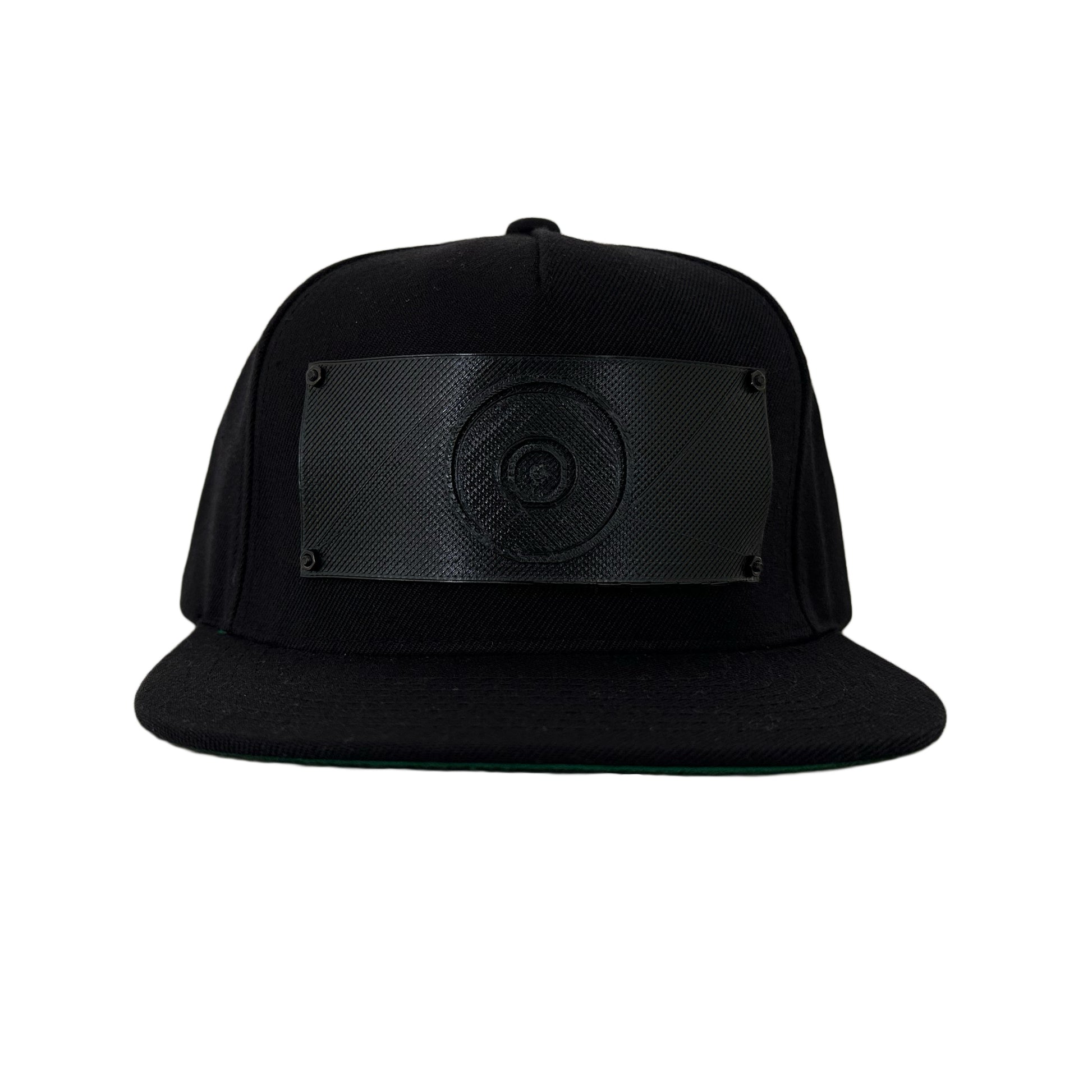 A black snapback baseball hat with a 3D printed black logo panel  with an evil eye symbol on it.
