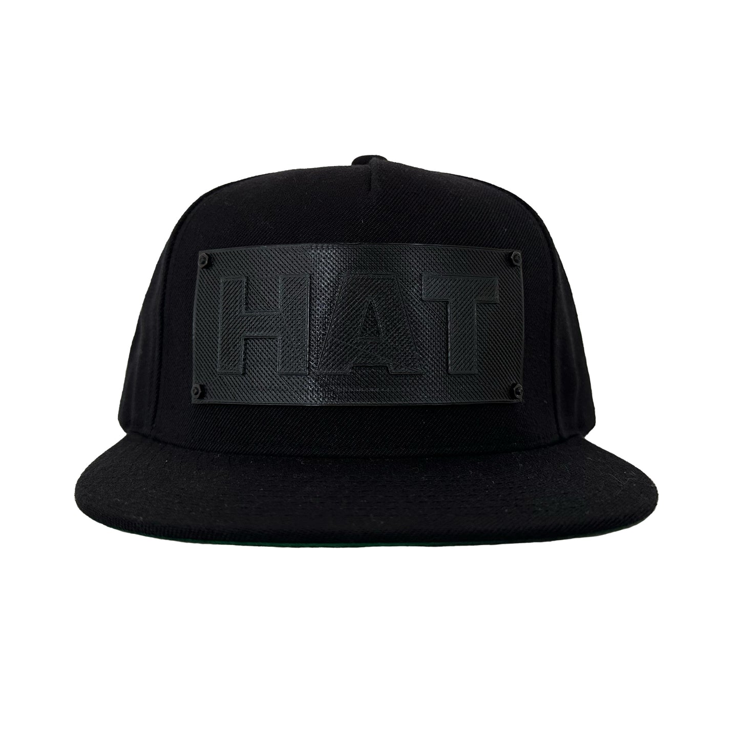 A black snapback baseball hat with a black logo panel that says"HAT".
