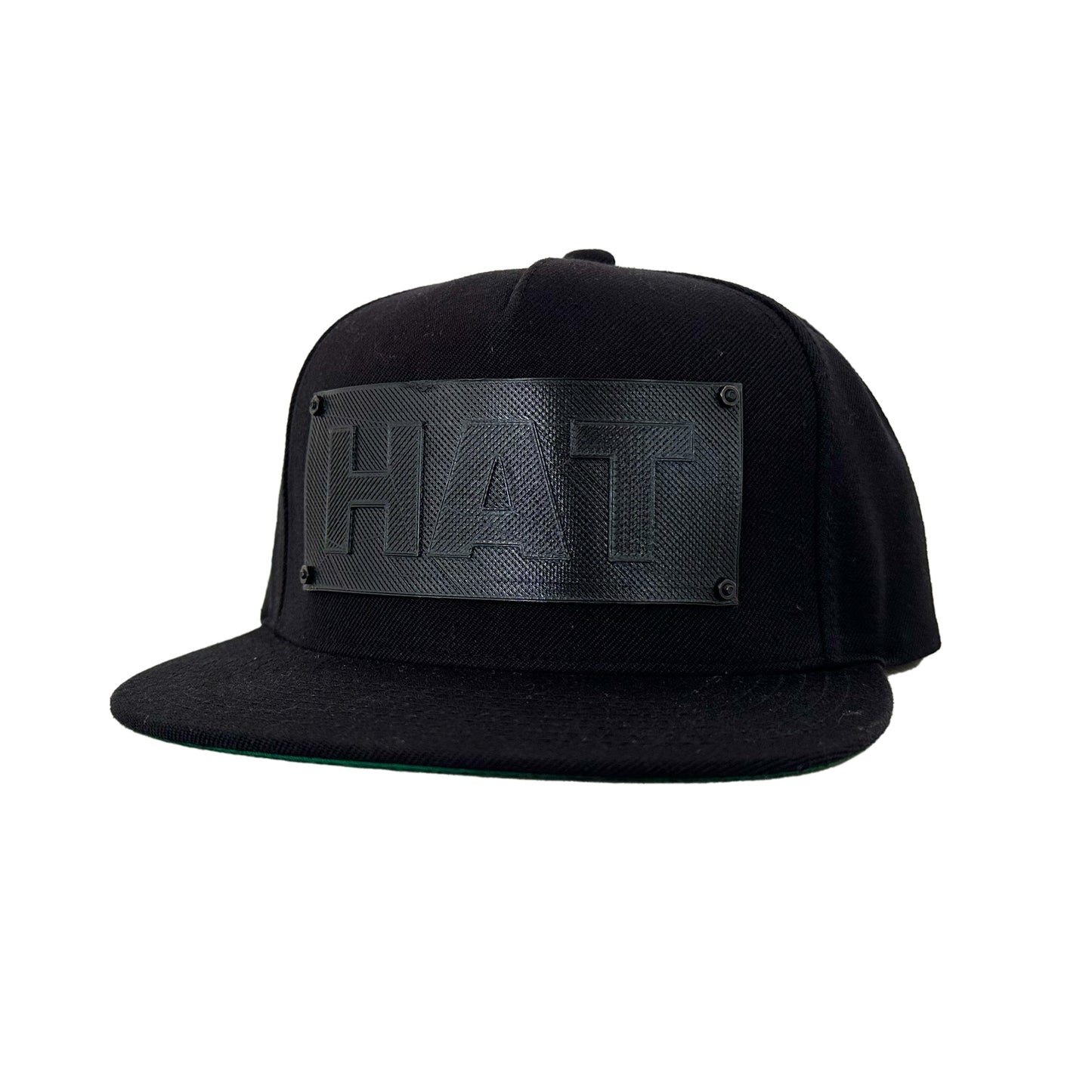 A black snapback baseball hat with a black logo panel that says"HAT".
