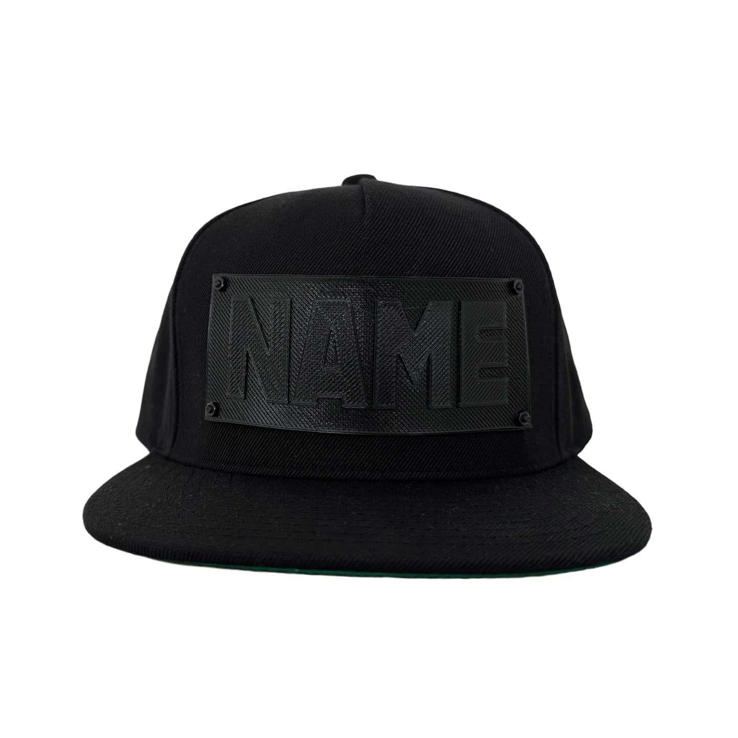 A black snapback baseball hat with a black logo panel that says"NAME".